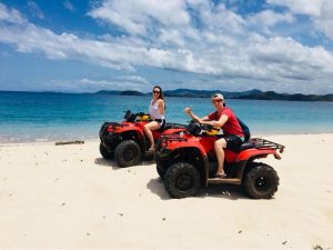 Hannah Page and friend riding ATVs on a beach